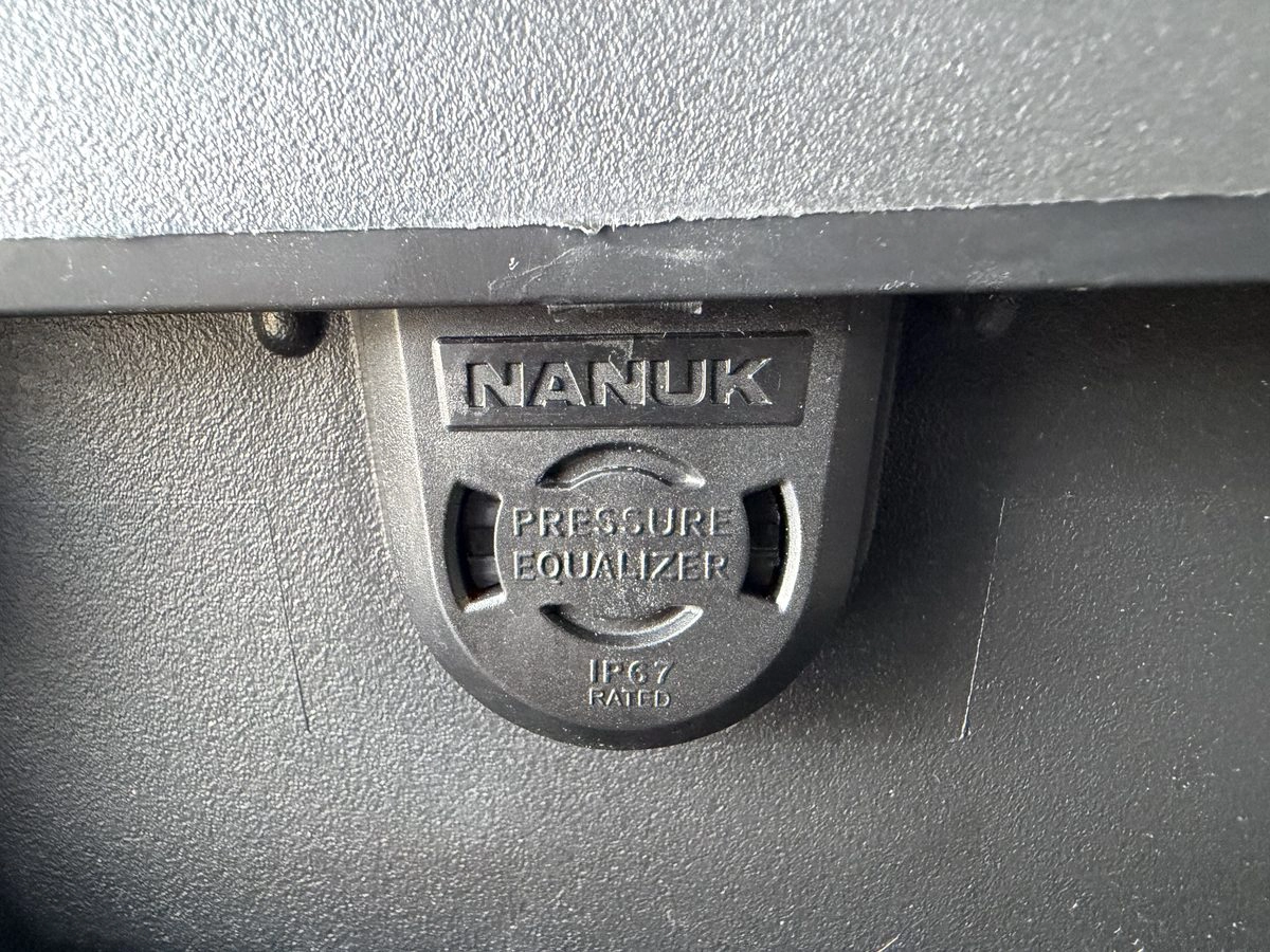 Close-up of Nanuk IP67-rated pressure equaliser valve on case side wall, showing NANUK branding and circular valve mechanism